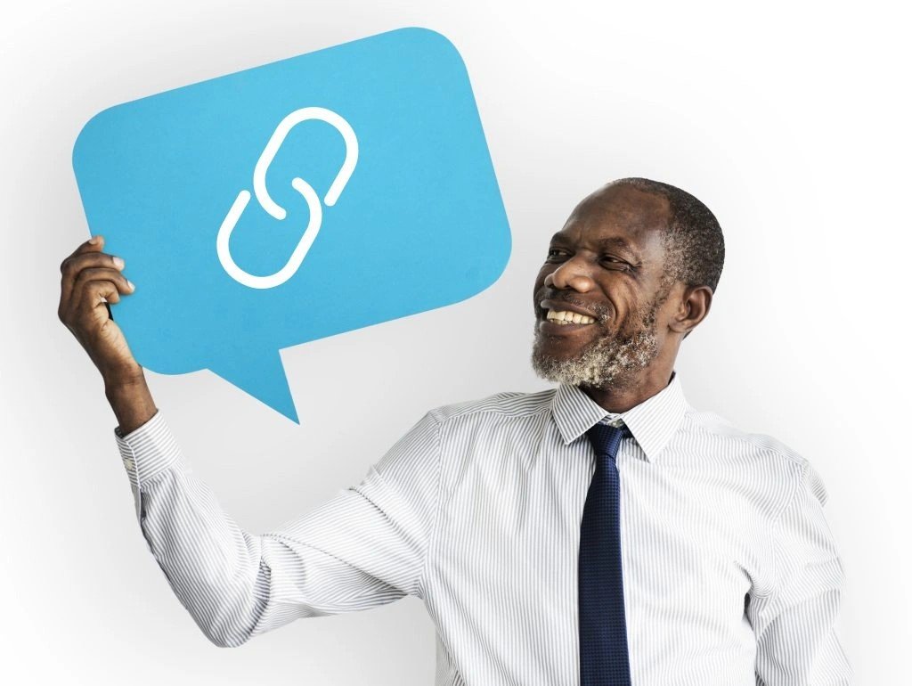 Smiling man holds a blue speech bubble with a white chain-link icon, symbolizing sharing or linking.